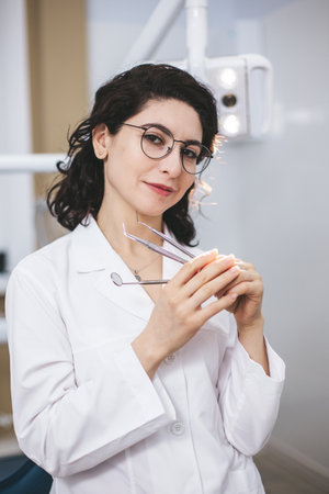 Professional young dentist posing confidently beside modern dental equipment in a dental clinic. Portrait of female doctor.の写真素材