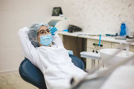 Female doctor dentist sitting on dentist chair after working day. Portrait of a woman stomatologist in clinic office.の写真素材