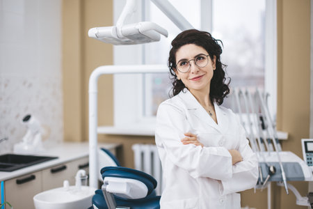 Professional young dentist posing confidently beside modern dental equipment in a dental clinic. Portrait of female doctor.の写真素材