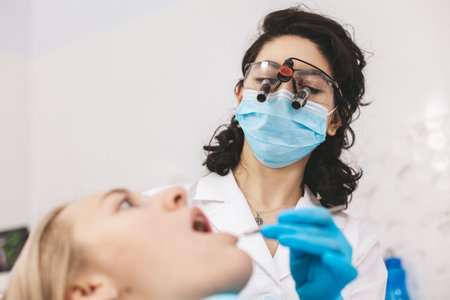 Female dentist examining patients mouth using stomatological binoculars. Using modern technologies in medicine.の写真素材