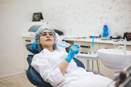 Female doctor dentist sitting on dentist chair after working day. Portrait of a woman stomatologist in clinic office.の写真素材
