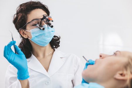 Female dentist examining patients mouth using stomatological binoculars. Using modern technologies in medicine.の写真素材