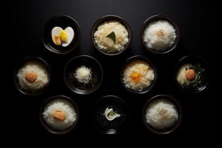 Bowls are filled with rice and vegetables, organized on black table.の素材