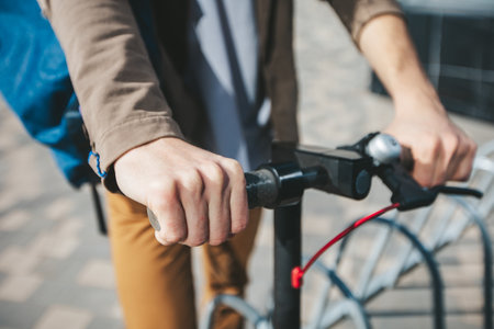 Urban mobility, man riding an electric scooter in a sunny city, highlighting sustainable transportation choices. City streets captured in the sunlightの写真素材