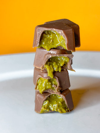 On an orange background, pieces of Dubai chocolate lie on a plateの写真素材