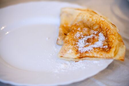 Pancakes on a white plate with powdered sugar, served for Breakfast
