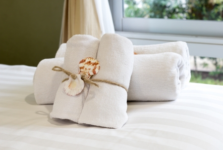 Closeup of soft white towels, rolled  folded and tied with rope and shell on bed の写真素材
