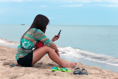Asian woman use mobile phone on the beach の写真素材