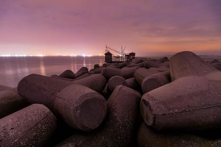 Red lighthouse at night with the light on the dam on the seaの写真素材
