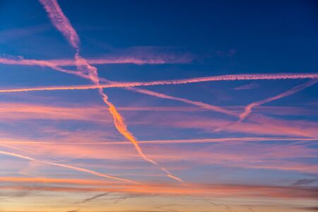 Texture of the sunset sky with red airplane trailsの写真素材