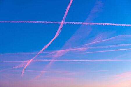 Texture of the sunset sky with red airplane trailsの写真素材