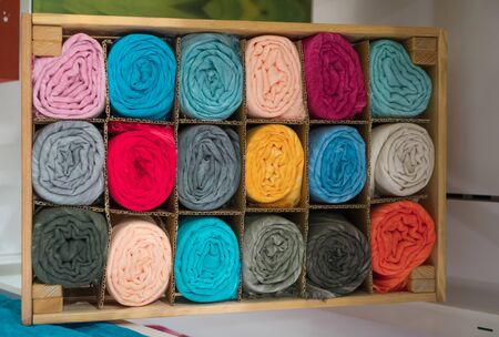 Many colored scarves for sale in the shop in a wooden cabinetの写真素材