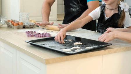 Family of Three Cooking Cookies Together at Home. Man in Kitchen Apron Rolling Out the Dough with a...