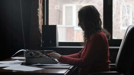Caucasian Woman Writer Using Typing Machine to Create Novel or Articleの写真素材