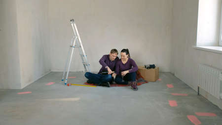 Young Couple Drinking Champagne and Celebrating Moving Day in New Home, Discussing Future Renovation