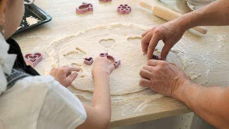 Little Girl with Father Cutting cookies of Dough and Putting it on a Baking Sheet