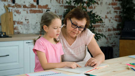 Little Girl Doing Homework for School with Grandmother at Home. Education, Teaching, Learning and...