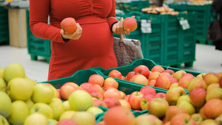 Close-up of Pregnant Woman Buying Apples at Grocery Storeの写真素材