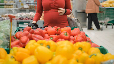 Pregnant Woman Buying Fresh Eggplant at Grocery. Healthy Food and Expectation of Baby Conceptの写真素材
