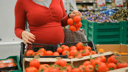 Pregnant Woman Buying Tomatoes at Grocery. Healthy Organic Bio Food for Future Mother Conceptの写真素材