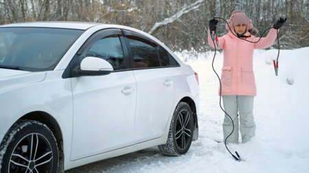 Confused Young Caucasian Woman Trying to Decide how to Use Starter Cables while Standing by the Car...
