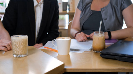 Close-up of business colleagues working together during lunch break, drinking coffee drinks at cafeの写真素材