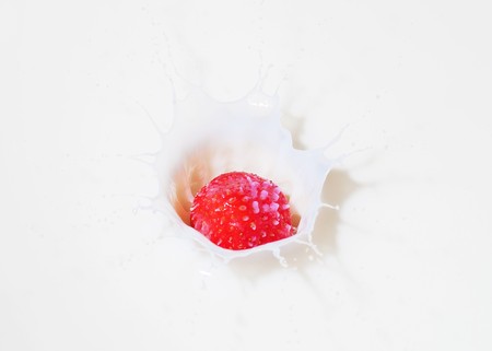 A fresh red strawberry splashing into milkの写真素材