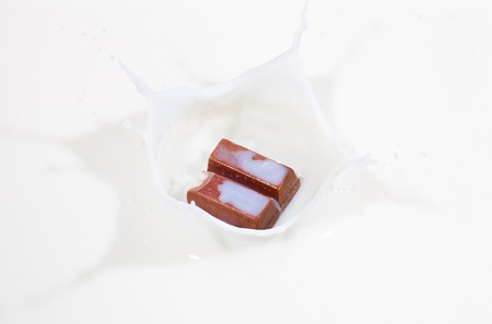 Chocolate candy splashing into white milkの写真素材