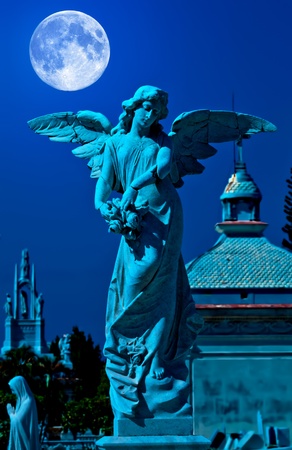 Angel in a cemetery at midnight with a bright full moonの写真素材