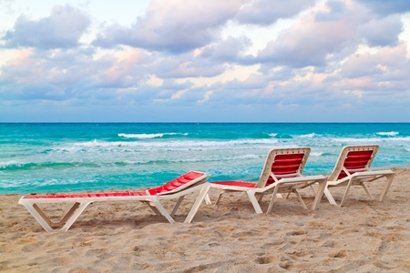 Three red reclining chairs on a beautiful tropical beachの写真素材