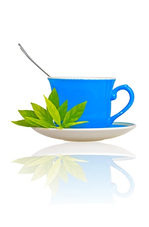 Blue tea cup with green leaves and a spoon on a white background with reflectionsの写真素材