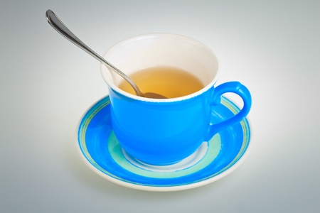 Blue tea cup with a spoon on a plate の写真素材