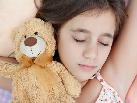 Latin girl sleeping with her teddy bearの写真素材
