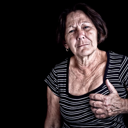Mature woman suffering from chest pain or depression on a black background with space for textの写真素材