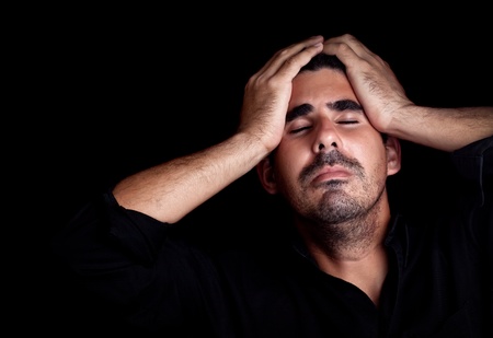 Portrait of a stressed and sad young man with a dramatic expression on a black backgroundの写真素材