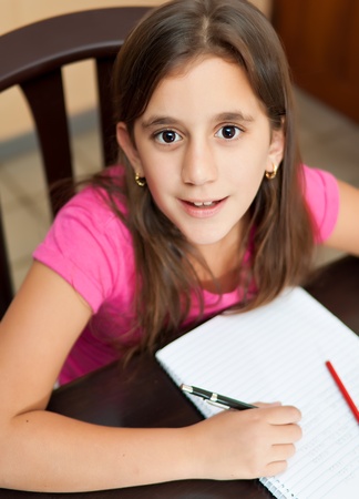 Beautiful latin girl working on her school homework and looking at the cameraの写真素材