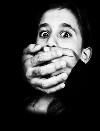 Dramatic black and white image of a girl being abused and silenced with two hands coming out of a...