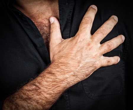 Close up of a hand grabbing a chest on a black background, useful to represent a heart attack or any...