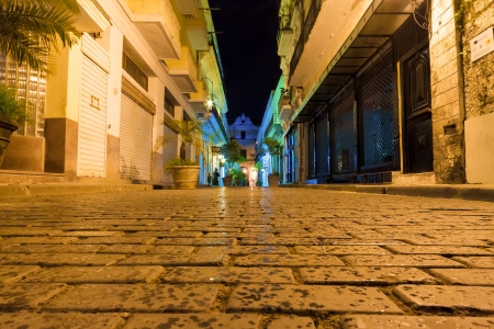 Narrow street sidelined by typical buildings illuminated at night in Old Havanaの写真素材