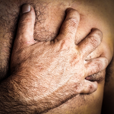 Close up of a hand grabbing the chest of a man who is suffering a heart attackの写真素材