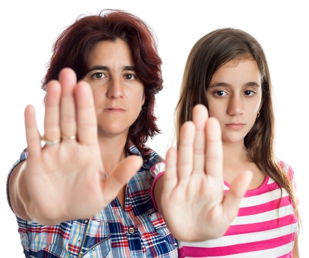 Young latin woman and a teenage girl signaling to stop with their hands extended isolated on white  useful to capaign against abuse,violence or discrimination の写真素材