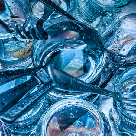 Macro image of blue toned cutlery and glasses being washed with waterの写真素材