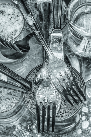 Cutlery and glasses being washed with water and detergentの写真素材