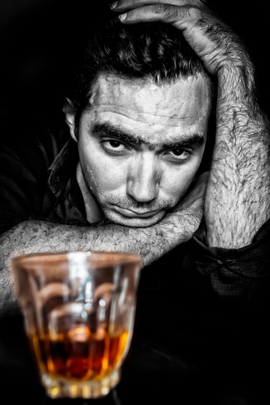 Black and white grunge portrait of a drunk and depressed hispanic man  with a contrasty golden alcoholic drink の写真素材