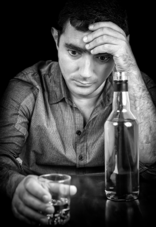 Black and white image of a drunk and sad hispanic man with a black backgroundの写真素材