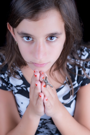 Hispanic girl praying with a crucifix in her hands  image taken from above の写真素材