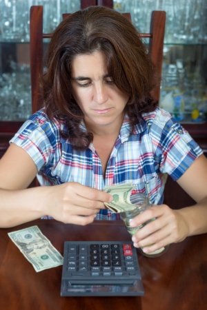 Worried hispanic woman counting her savings at home   useful to illustrate economic problems or difficulty to make ends meet の写真素材