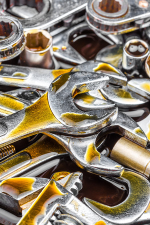 Heap of shiny metallic tools  wrenches and spanners  with motor oil stainsの写真素材