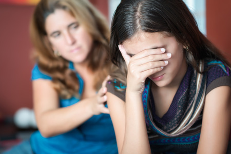 Teenager problems - Mother comforts her troubled teenage daughter who criesの写真素材