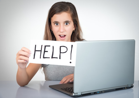 Helpdesk and computer support - Child working with a laptop and holding a sign with the word Help!